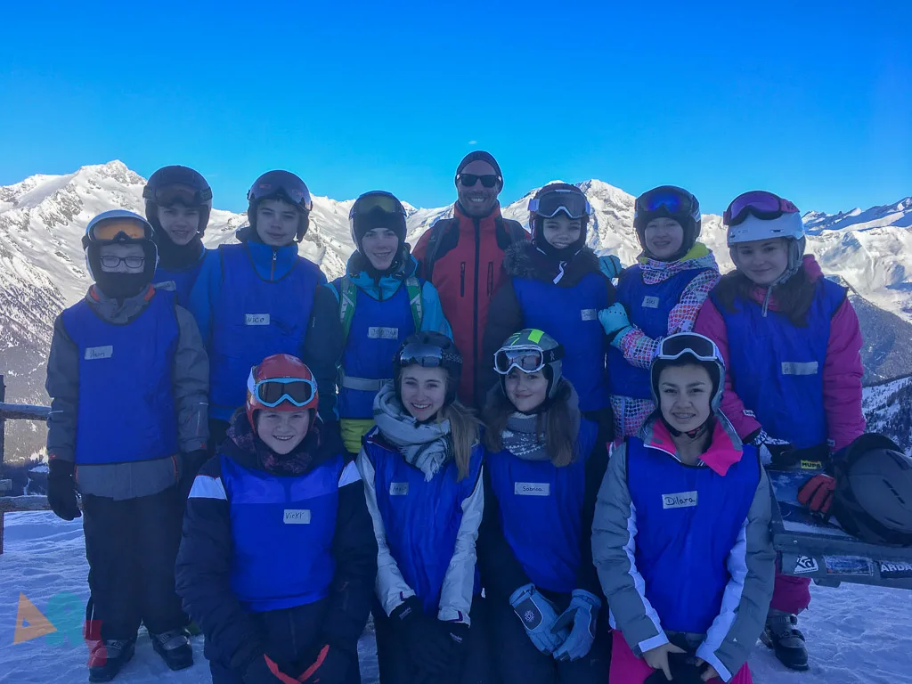 Skigruppe posiert vor tiefblauem Himmel.
